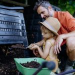 Vater und Tochter holen Kompost aus dem Komposter