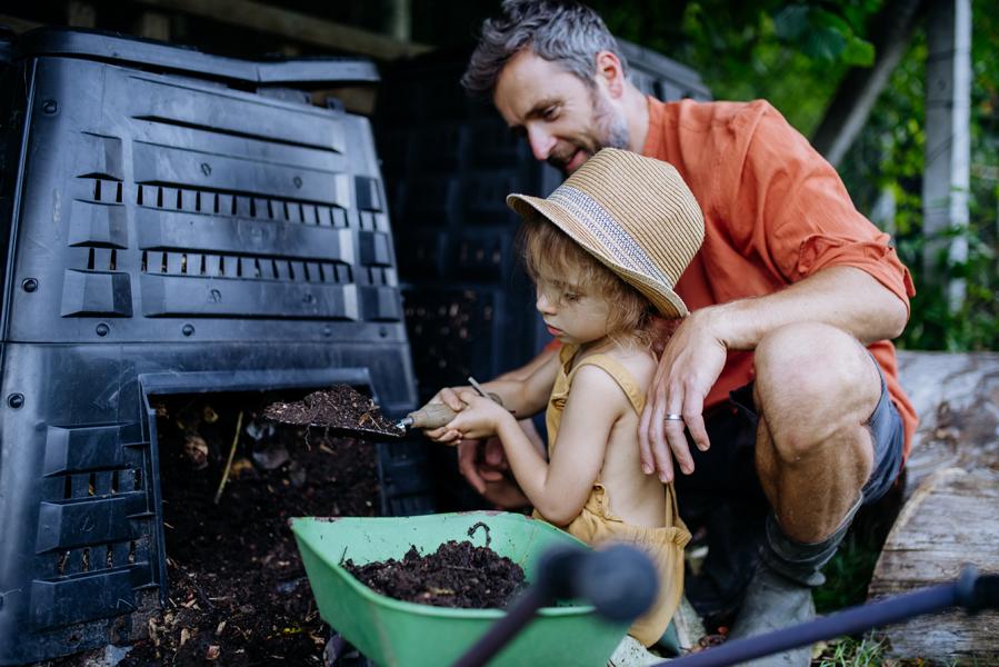 Vater und Tochter holen Kompost aus dem Komposter